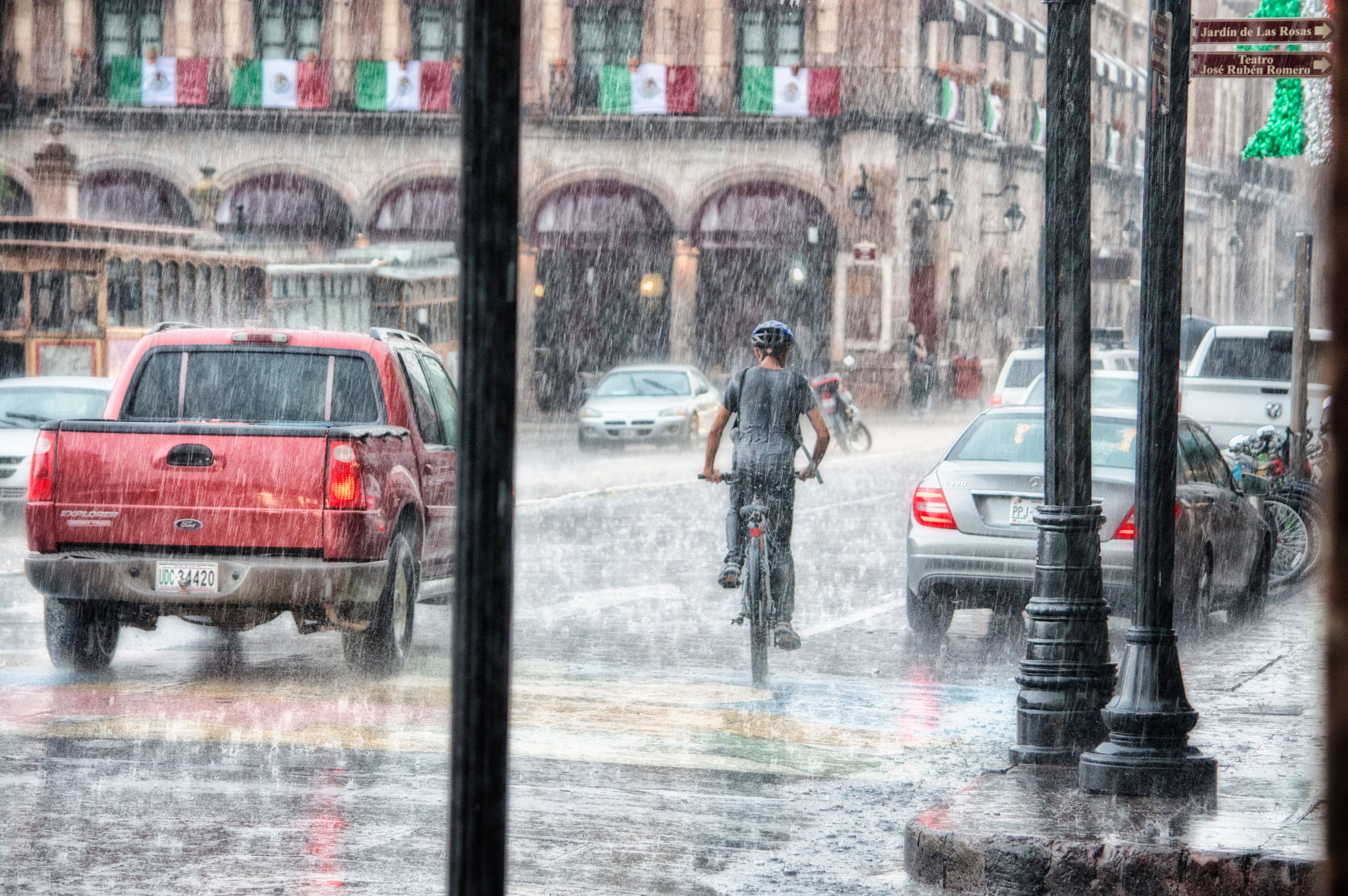 Fietser rijdt door een stevige regenbui op een natte straat