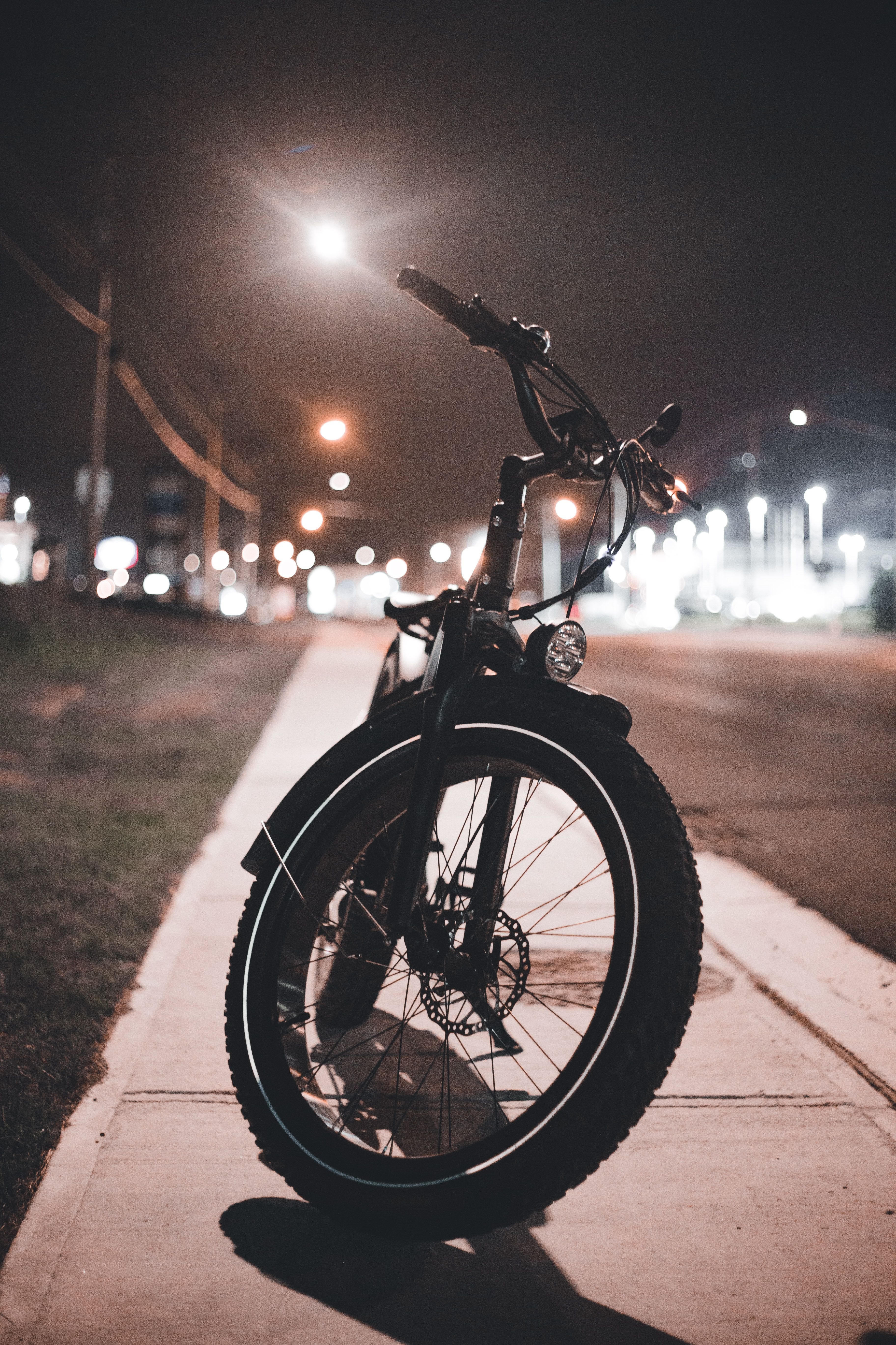 Fiets met verlichting op een stoep in het donker, verlicht door straatlantaarns