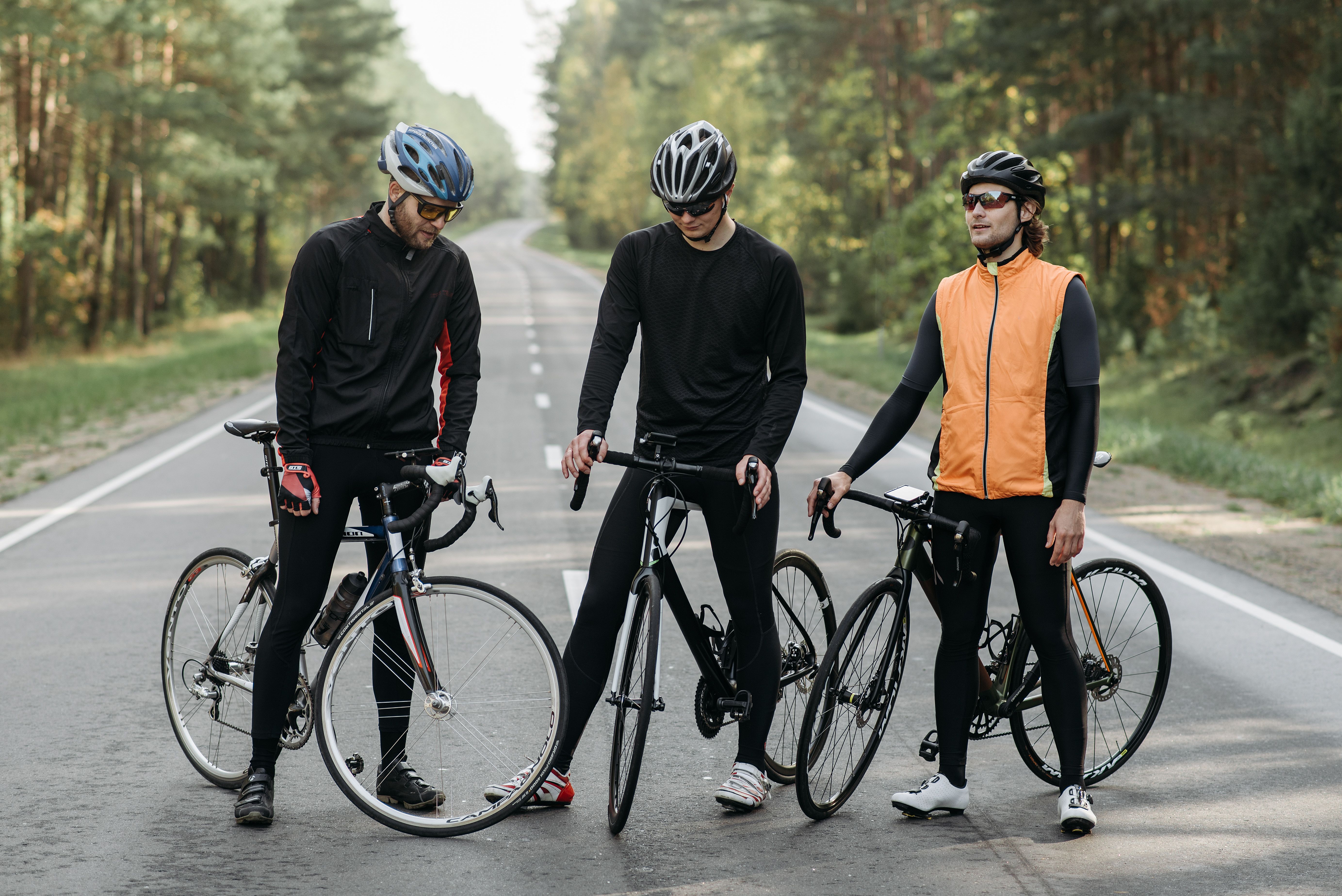 Drie fietsers in fietskleding en helm pauzeren langs een landweg tijdens een meerdaagse tocht