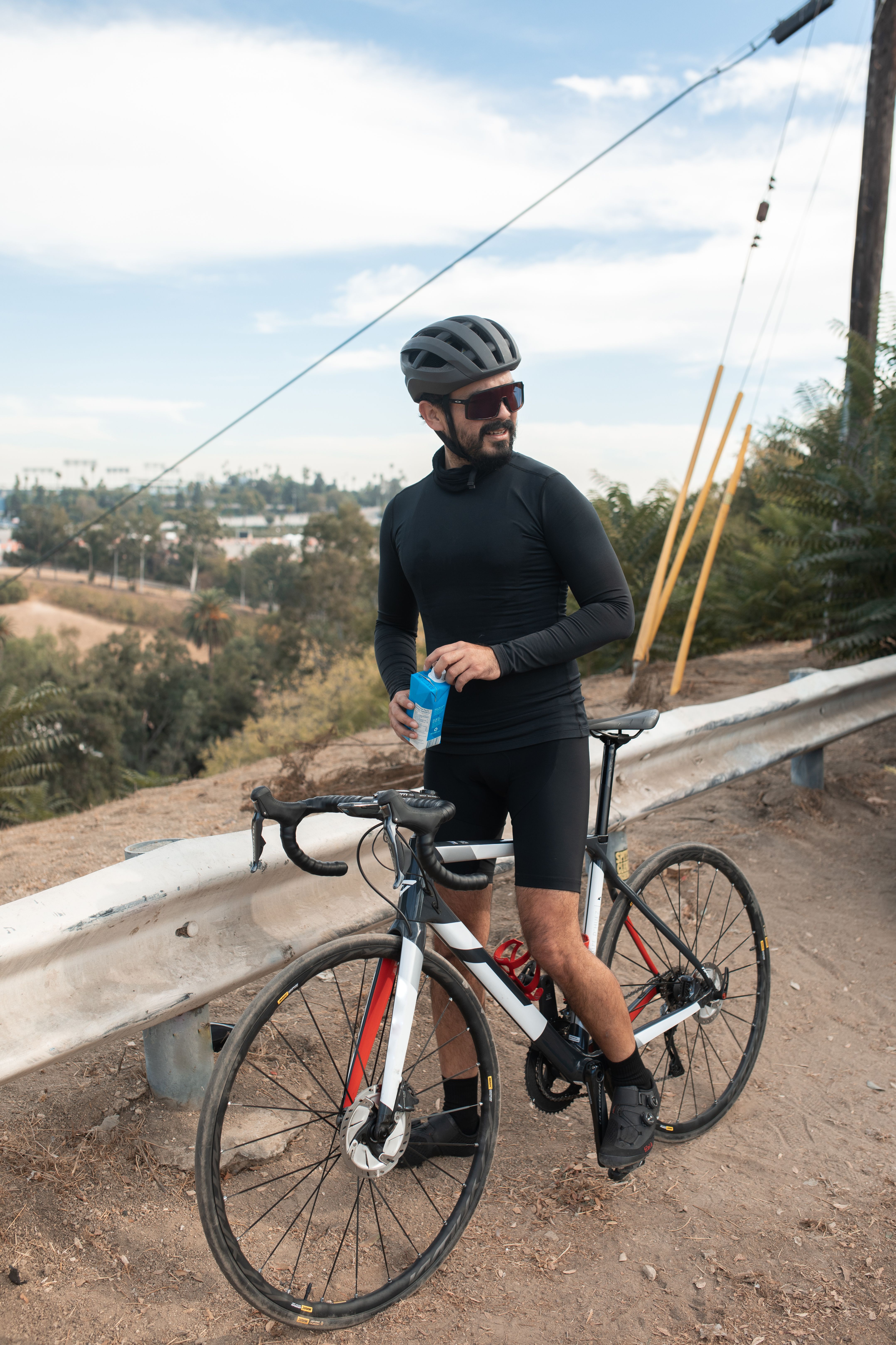 Fietser pauzeert langs een zonnige weg om te drinken tijdens een warme fietsdag